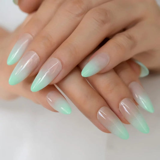 A person showing off a fresh set of mint green nails with gold ring accessories.